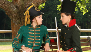 Juliette and Deny - beautiful teenie Deny, darker hair, is sitting on a bench dressed in antique army clothes, when luscious minx Juliette, green antique jacket approaches her. They are tired from reenacting historic battles, so Juliette sits beside Deny 